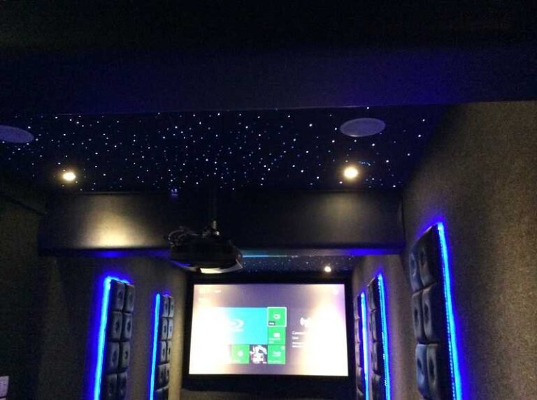 Dedicated home cinema with a star ceiling, blue accent lighting and a projection screen in a Versova penthouse