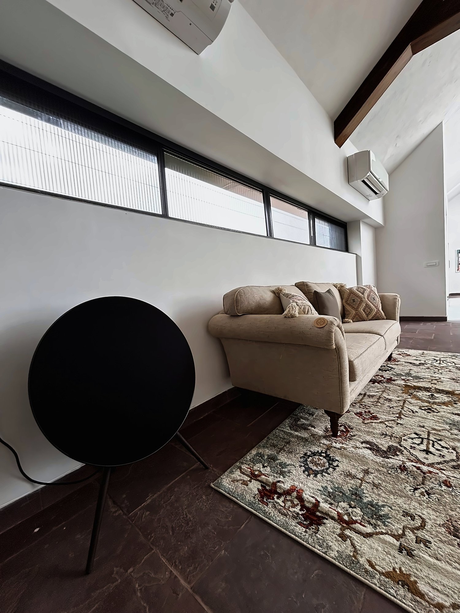 Round sculptural speaker beside a sofa
