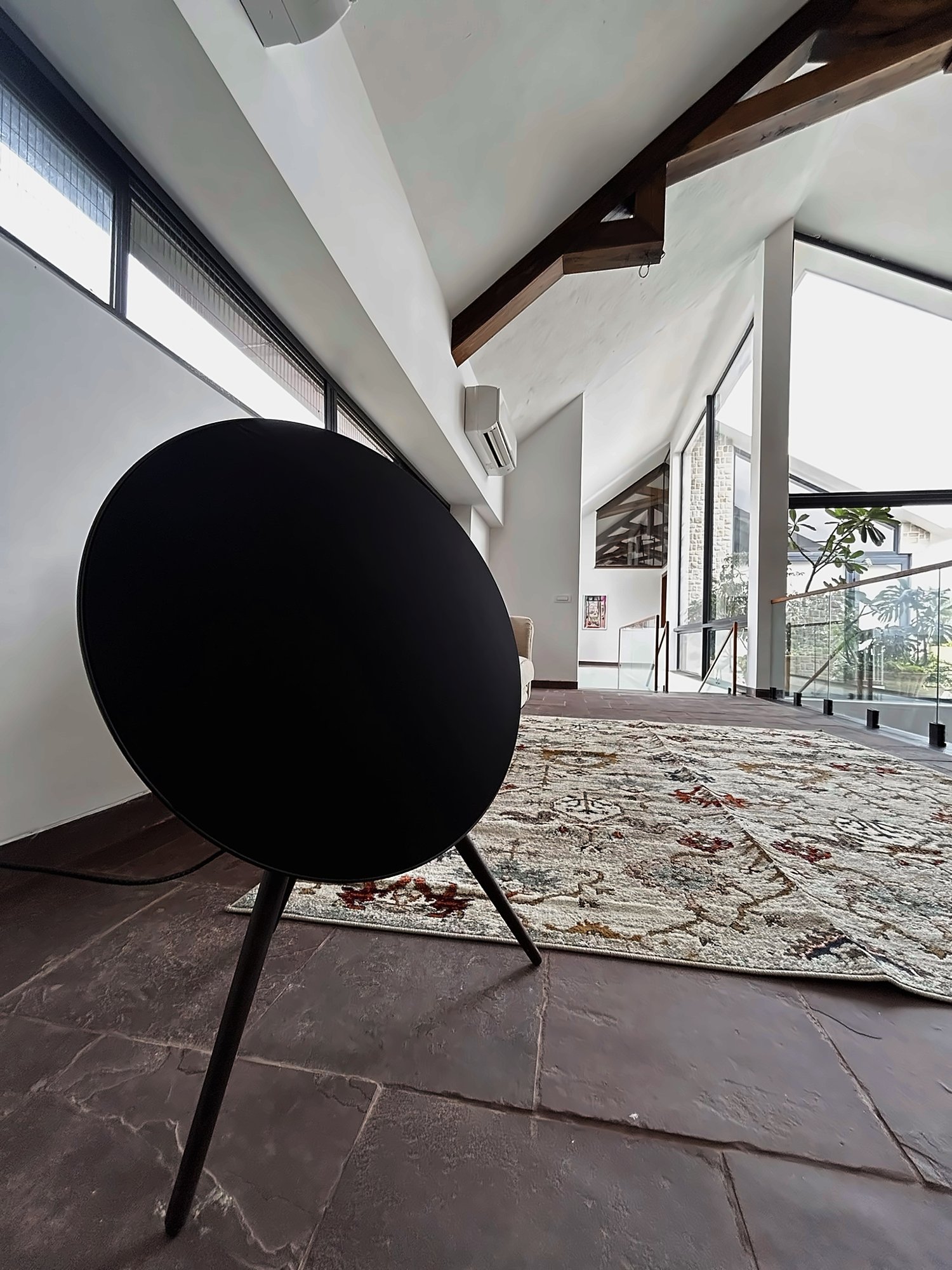 Sculptural speaker under timber trusses in a living room