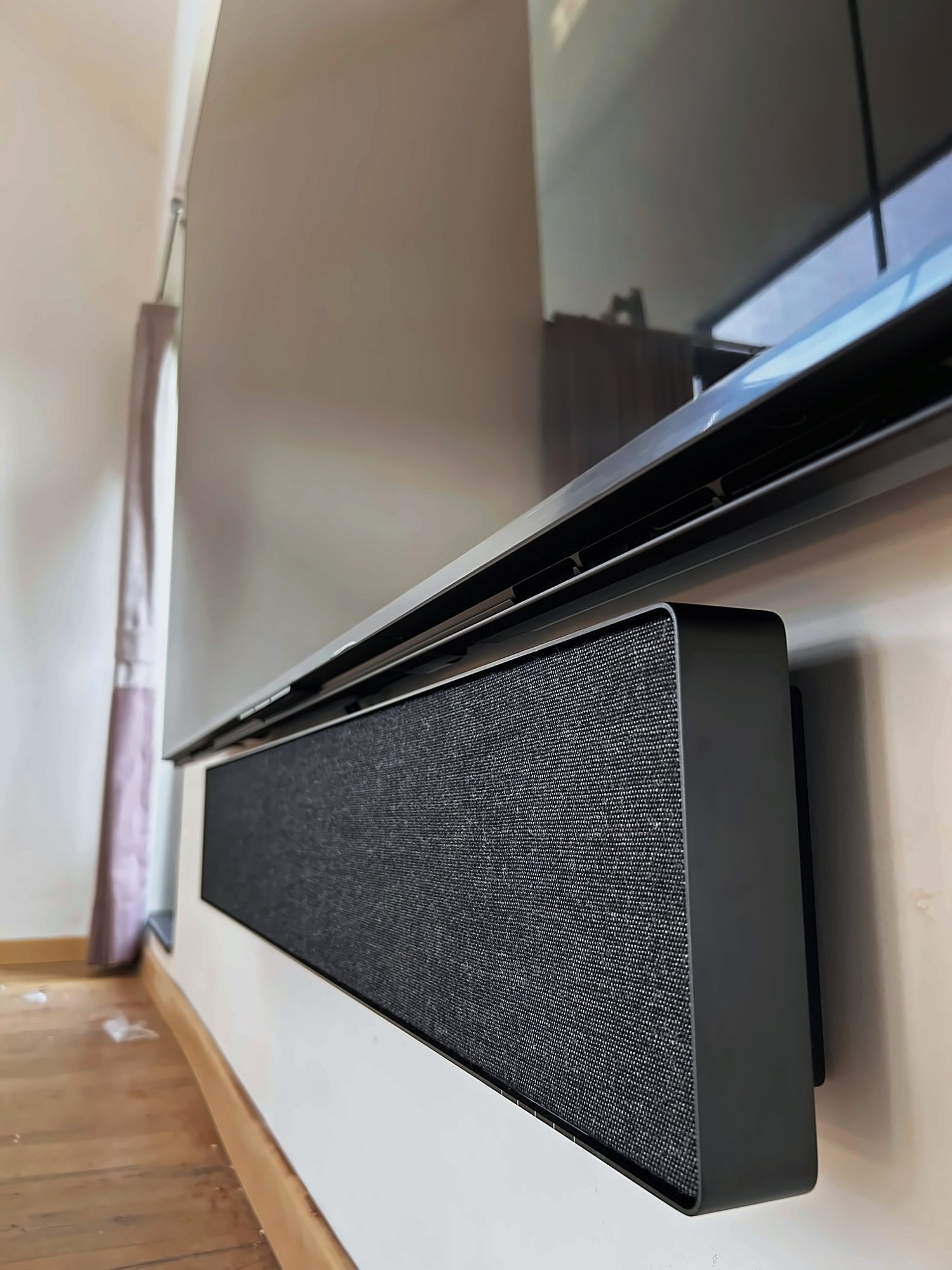 Soundbar sitting flush under a wall-mounted screen