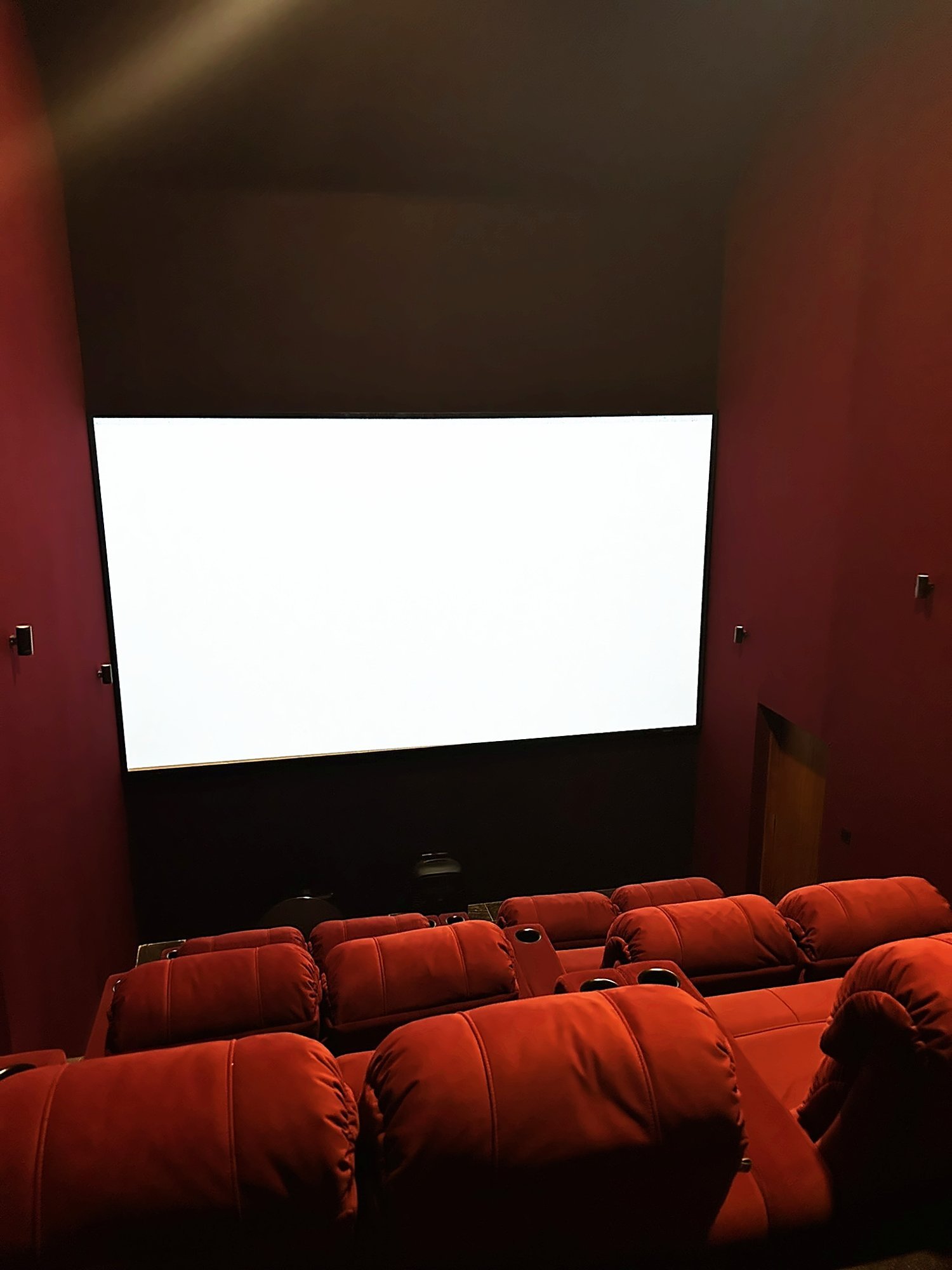 Private home theatre with deep red walls and tiered seating