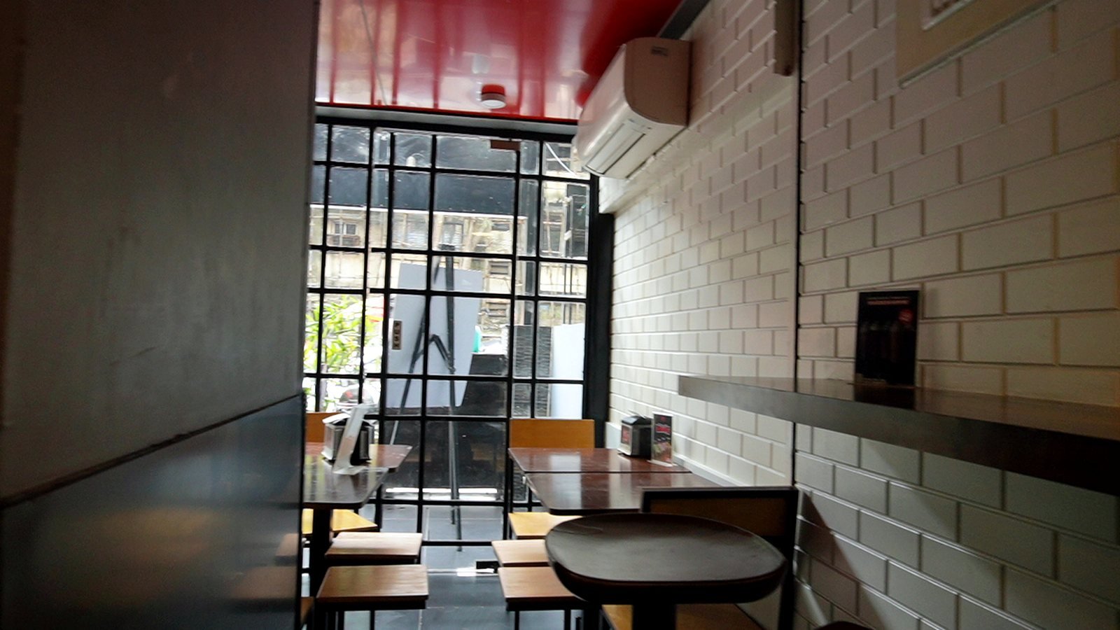 Dining area of a burger restaurant in Bandra with brick walls and window seating