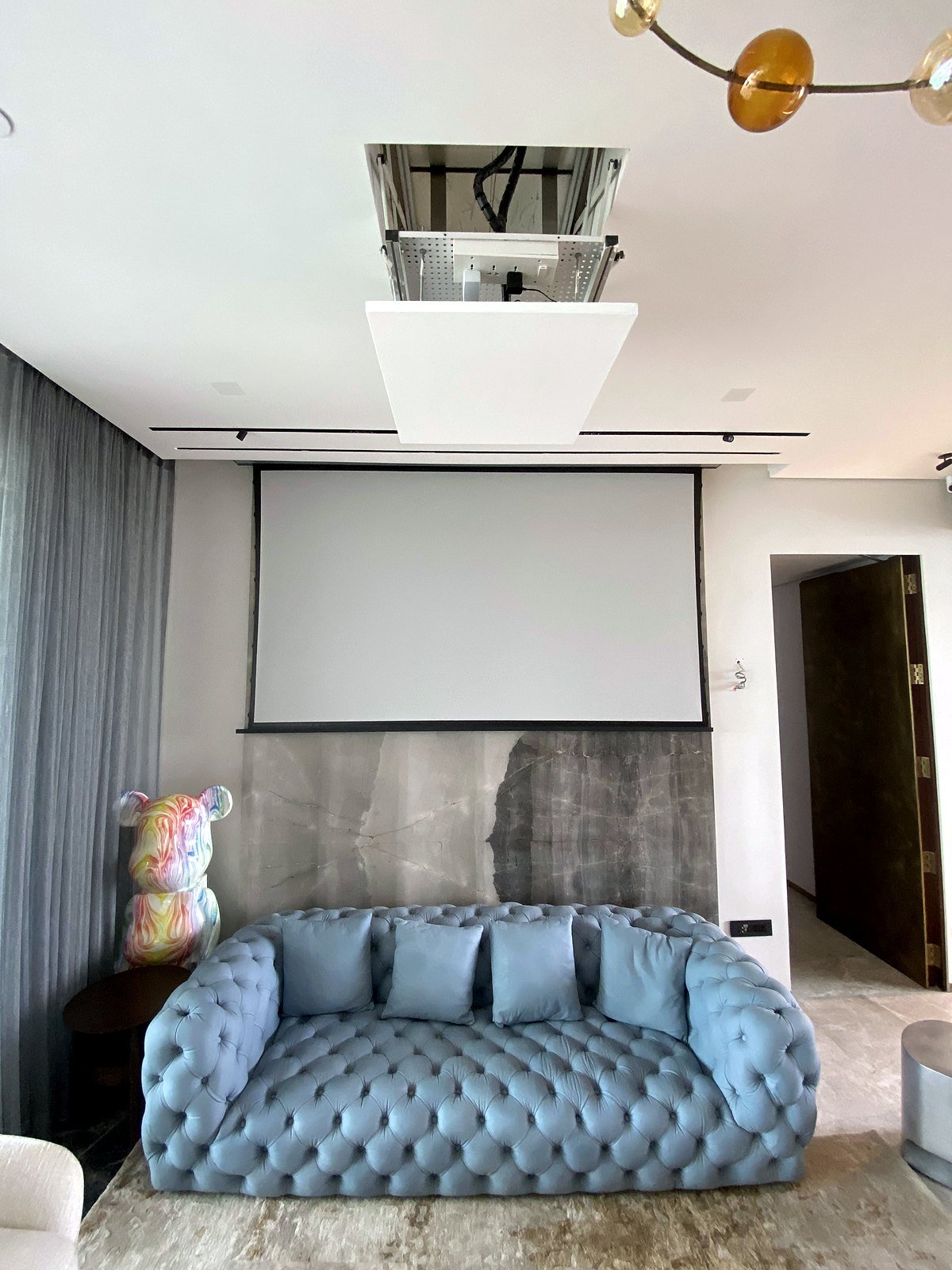 Living room of a smart apartment in Bandra, Mumbai with the 120-inch motorised screen lowered and the projector lift above it