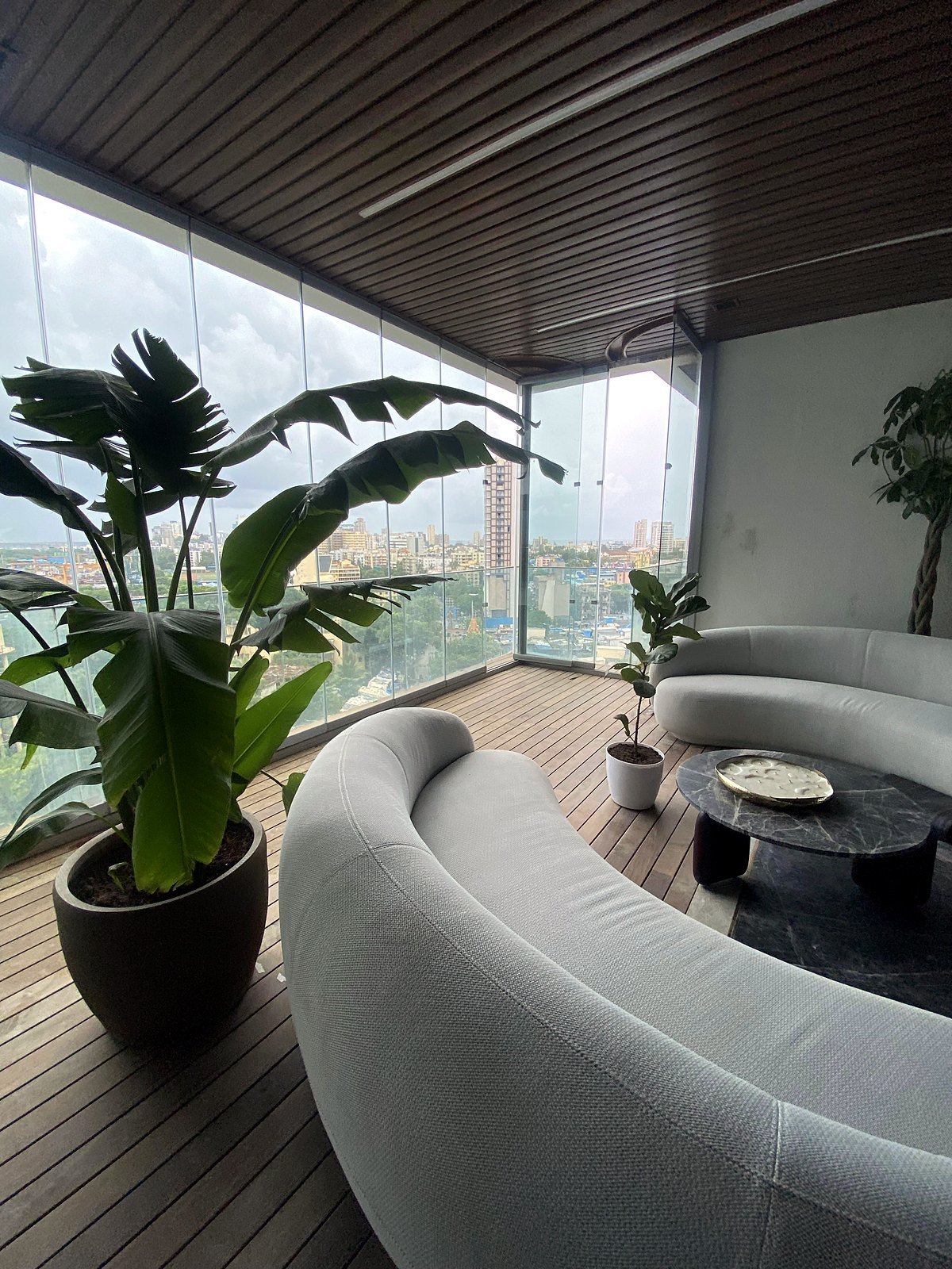 Living balcony lounge in a Bandra apartment with curved seating and a sea-facing glass wall