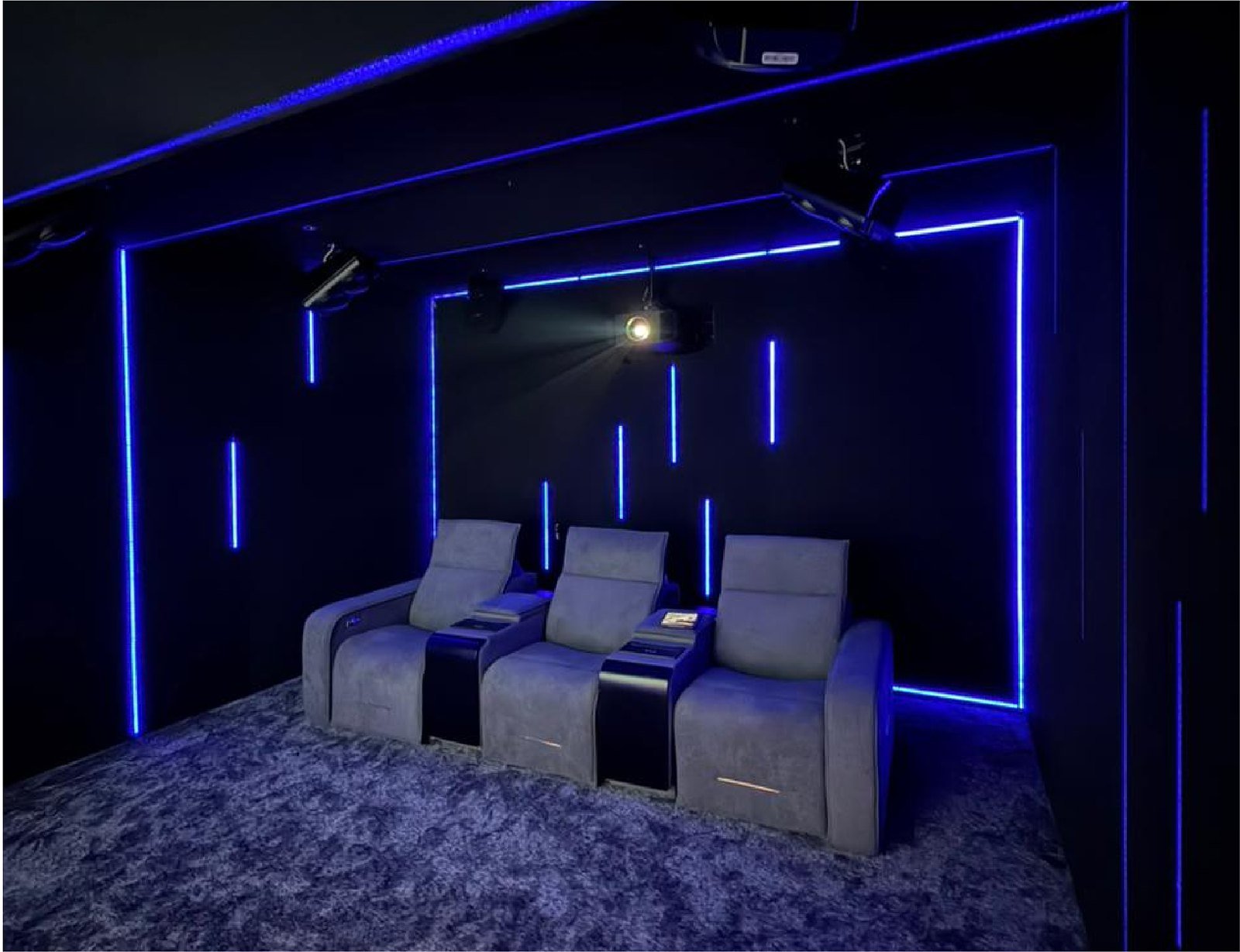 Dedicated home theatre with three grey recliners, blue LED accent lighting and ceiling-mounted projector at the Avenue Sound experience centre, Devanahalli, Bangalore