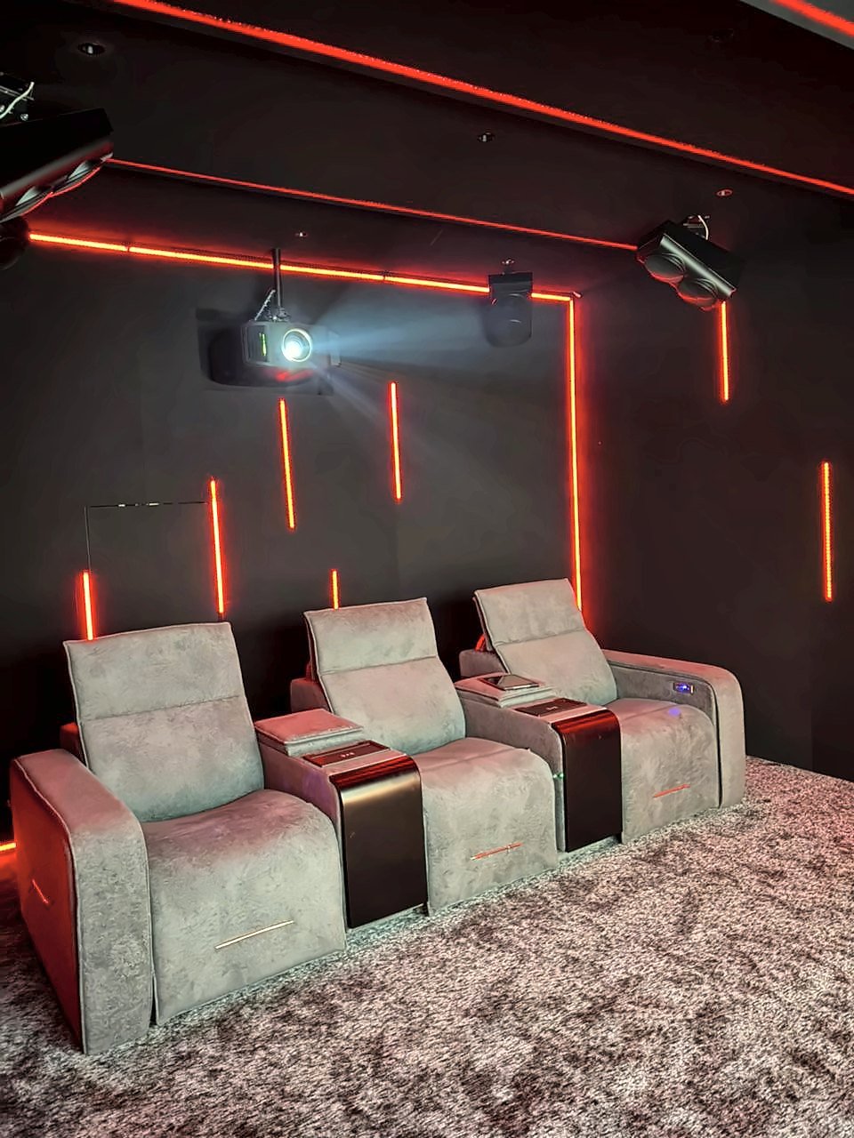 Home theatre recliners with red accent lighting, projector and ceiling speakers in the Devanahalli demo theatre, Bangalore