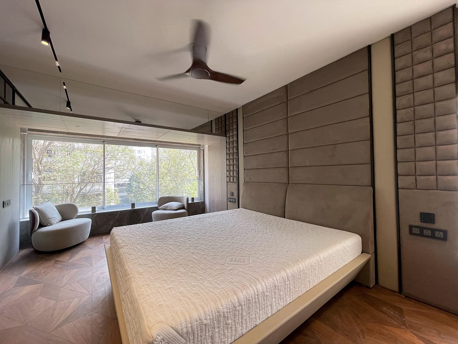 Bedroom of a Cuffe Parade smart apartment with ceiling fan and curtains