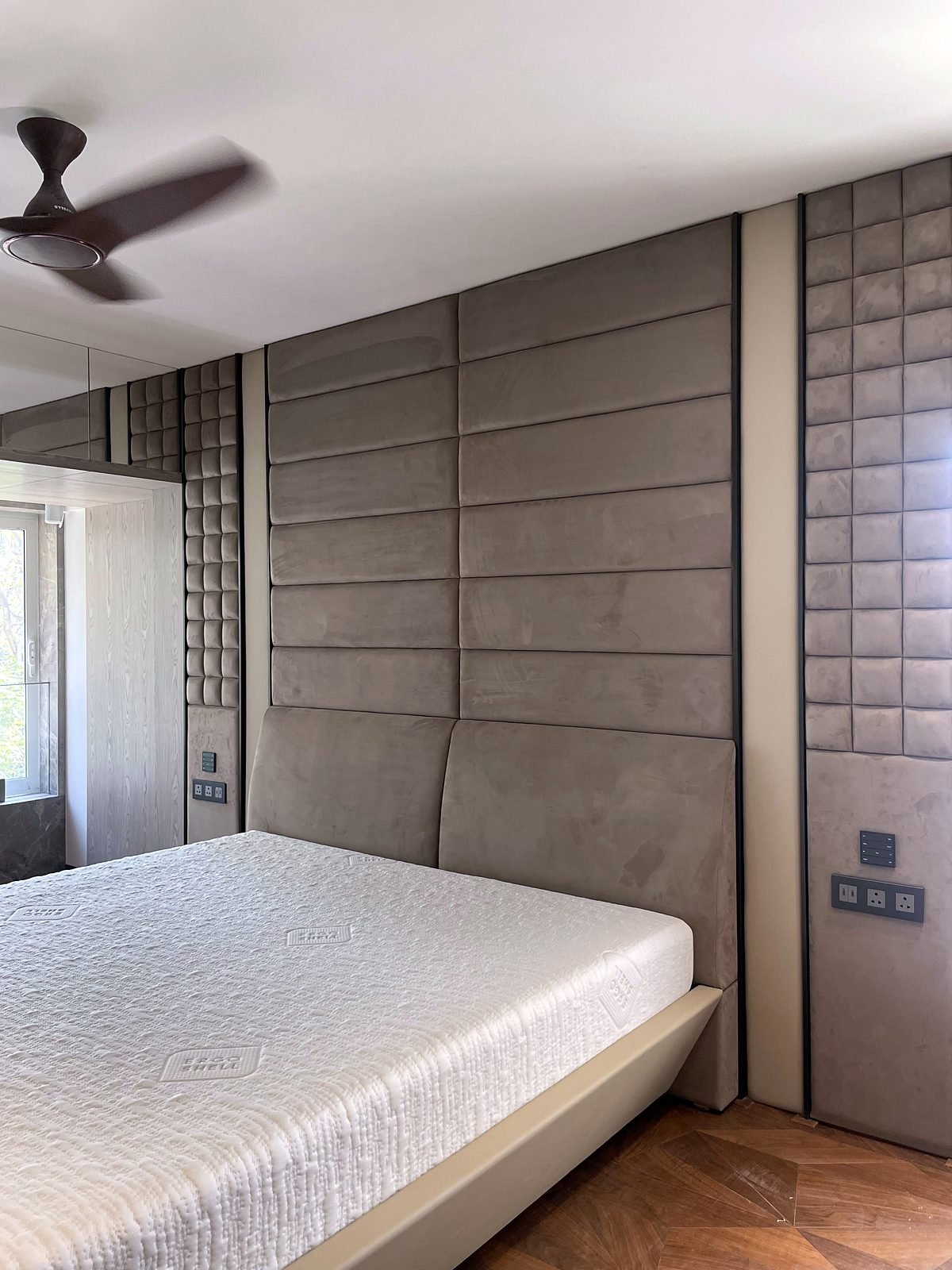 Bedroom in a Cuffe Parade apartment with a padded headboard wall, ceiling fan and wall keypad