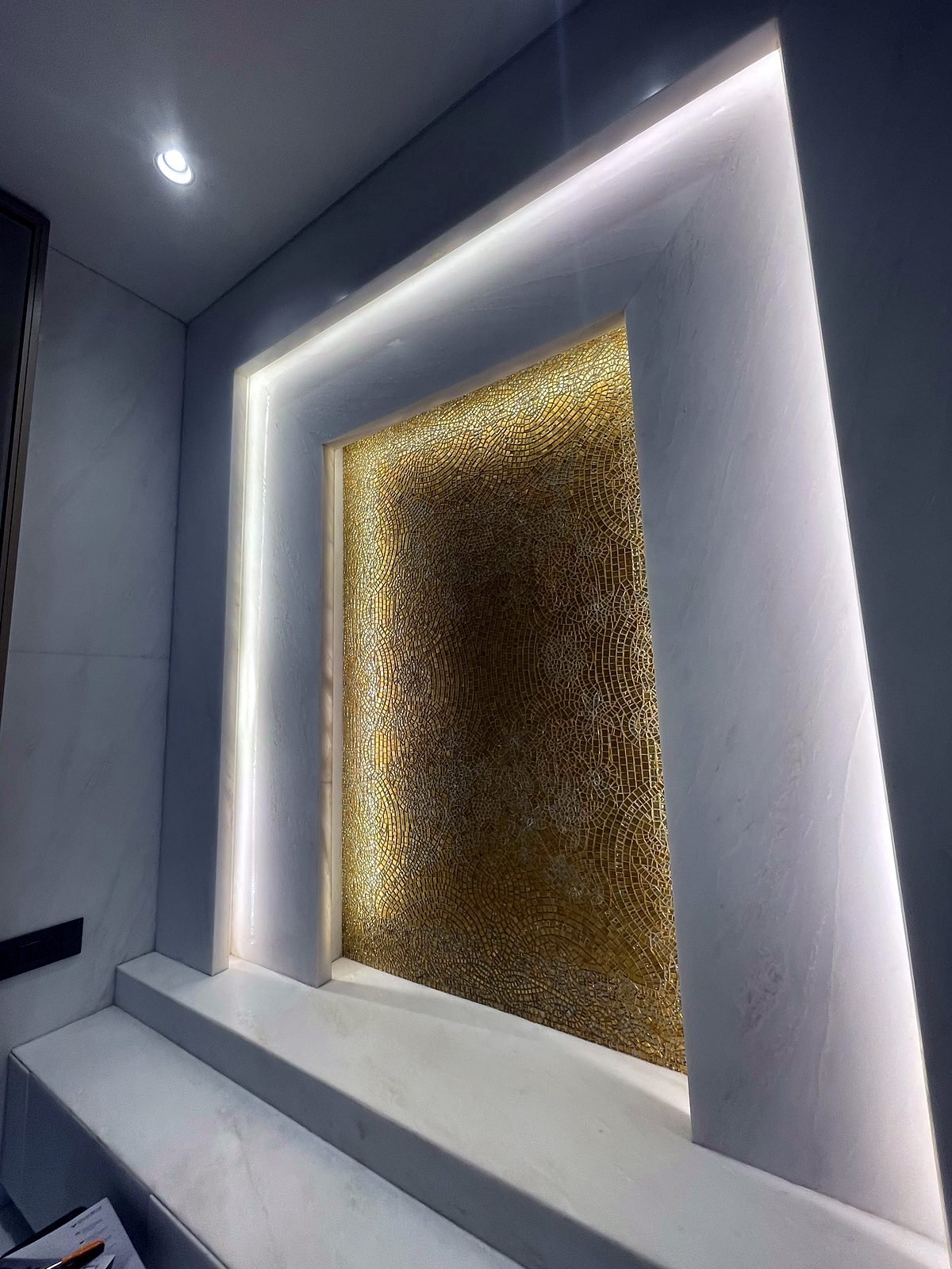 Lit feature niche with a gold-toned panel in the entrance area of a Cuffe Parade apartment
