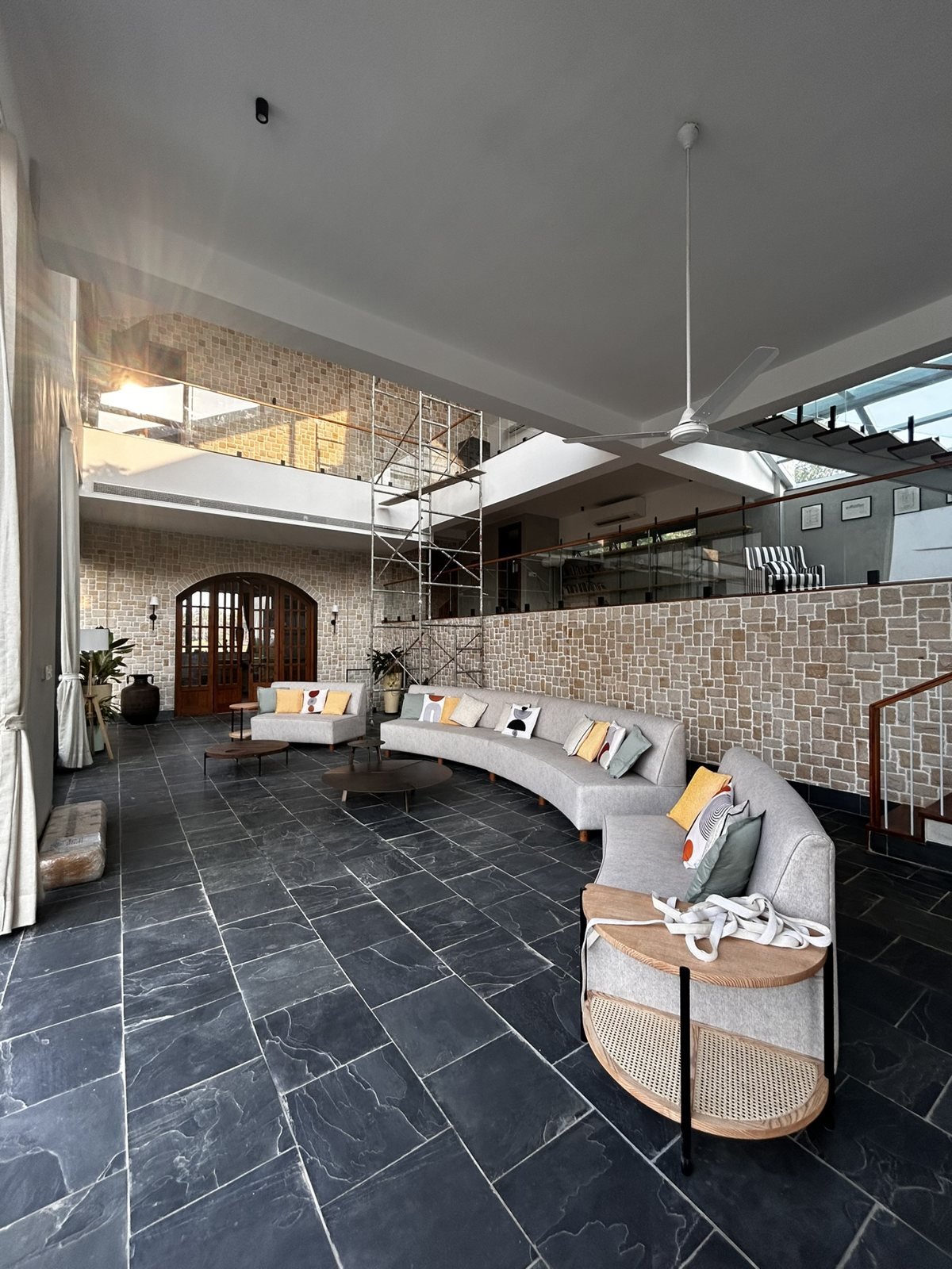 Wide lounge in a Goa villa with a curved sofa, slate floor and open terrace views