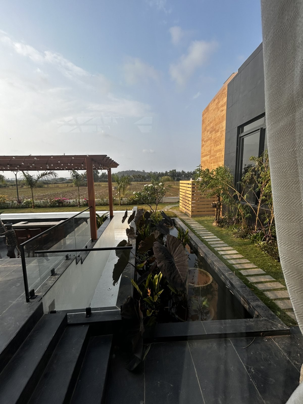 Villa terrace in Goa with a glass balustrade, steps and a water feature