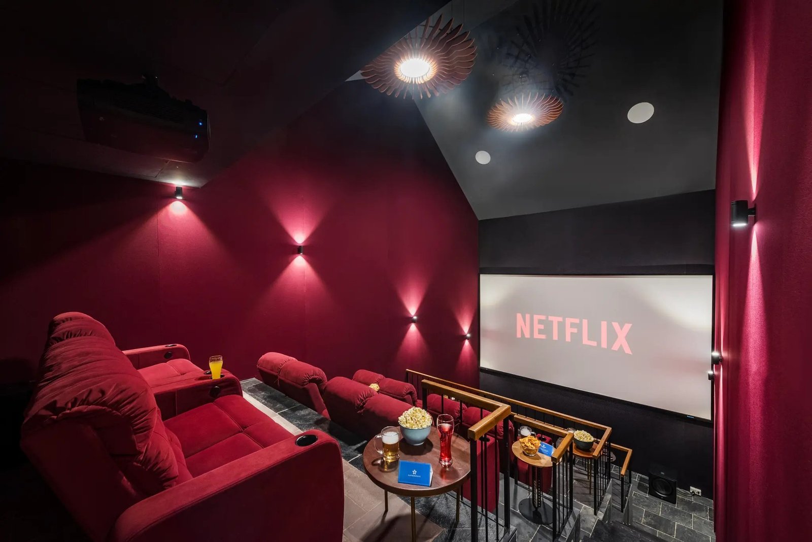 Dedicated home theatre in a Goa villa with red velvet recliners, tiered seating and a large screen