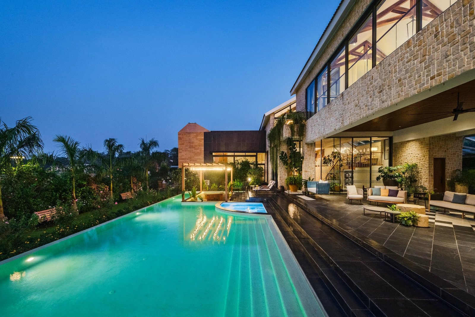 Infinity-edge pool and villa lit at dusk in Goa