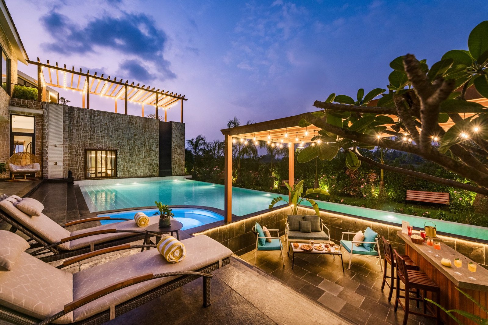 Pool deck with sun loungers and pergola at dusk in a Goa villa