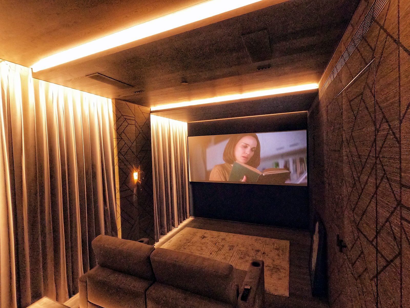 Lower Parel home theatre with full-height curtains drawn on both sides of a large projection screen showing a film