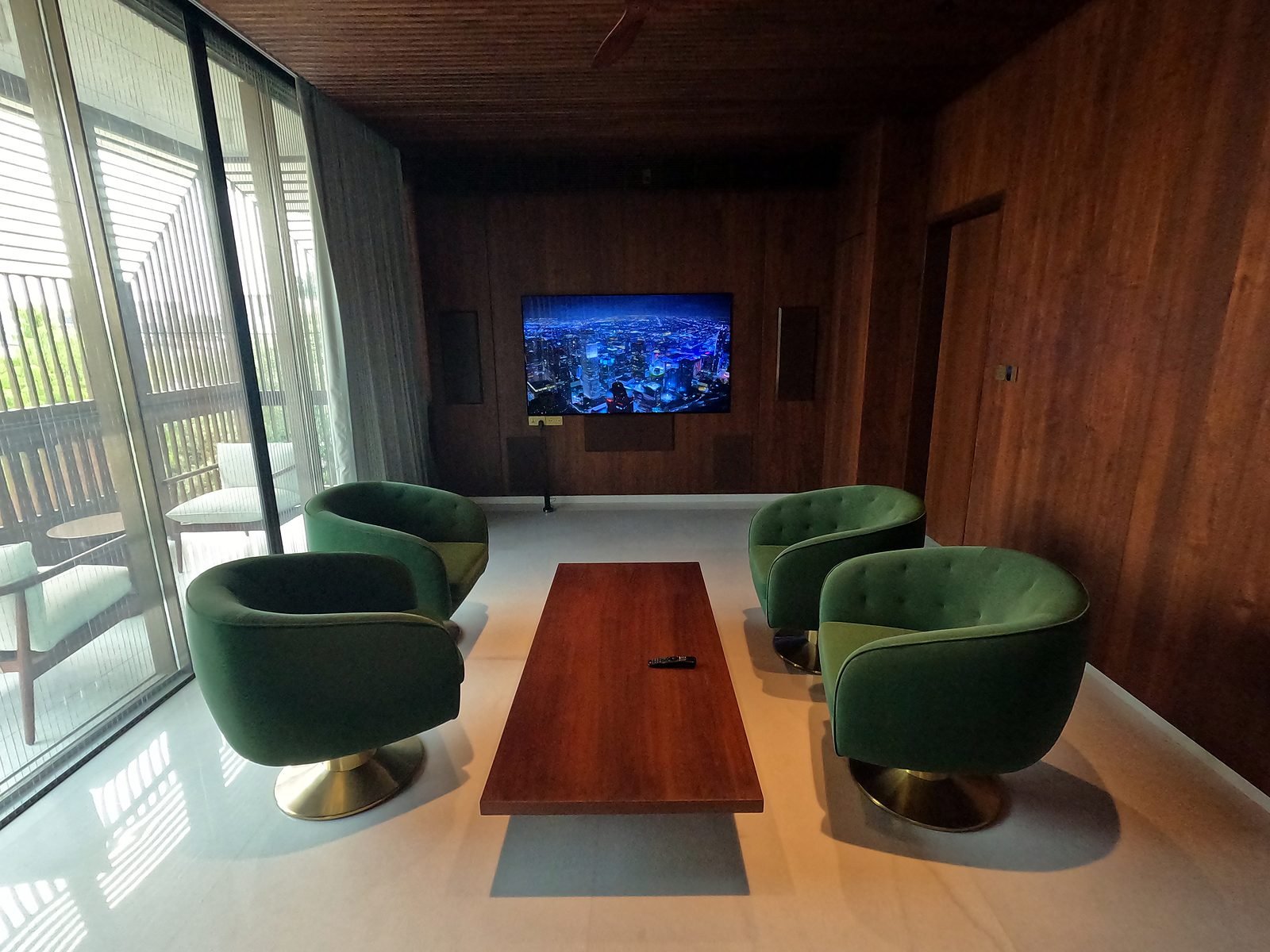 Bright lounge with TV and armchairs beside floor-to-ceiling windows in Nagpur