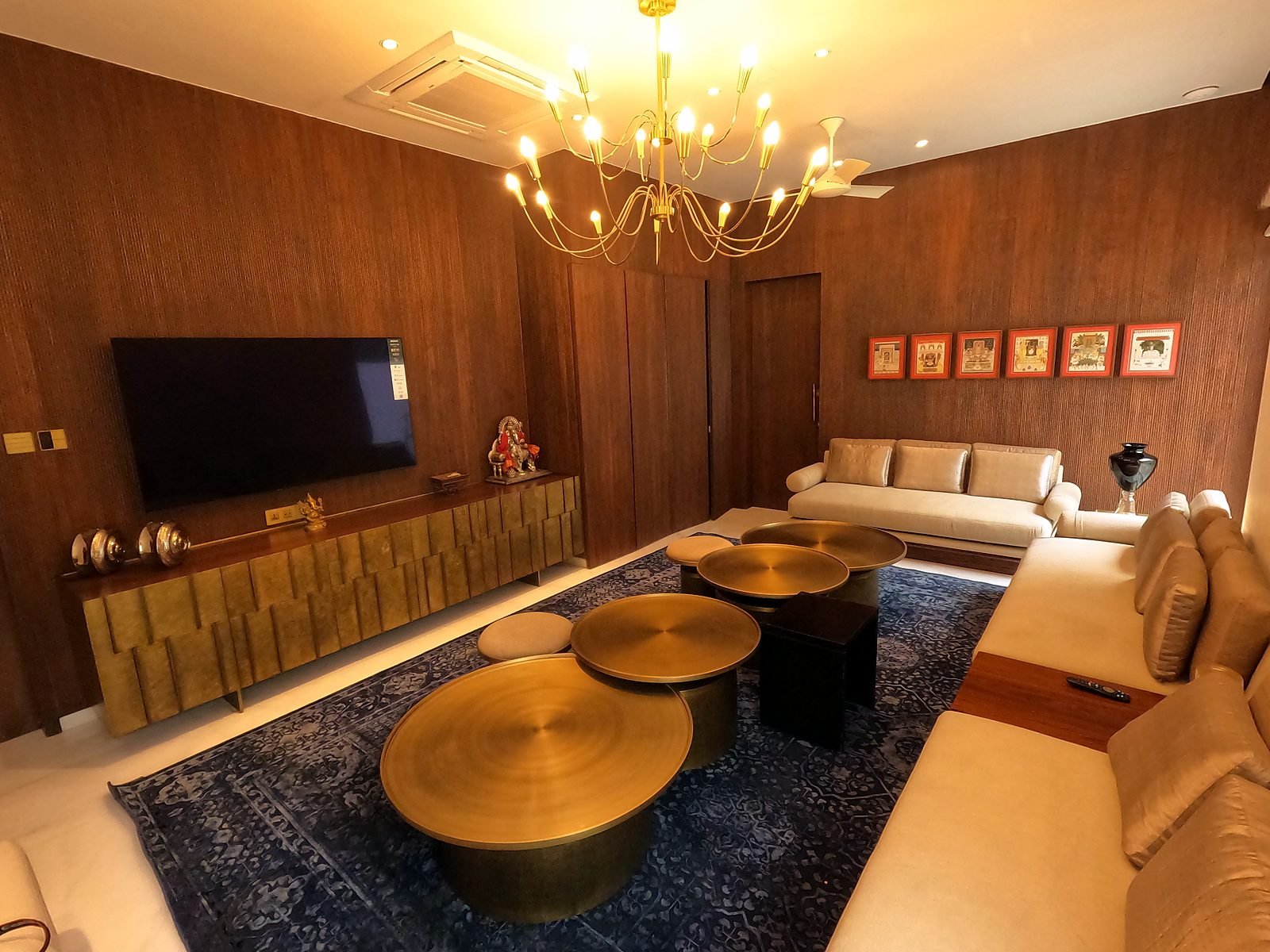 Formal living room with chandelier and wood TV wall in a six-storey Nagpur mansion