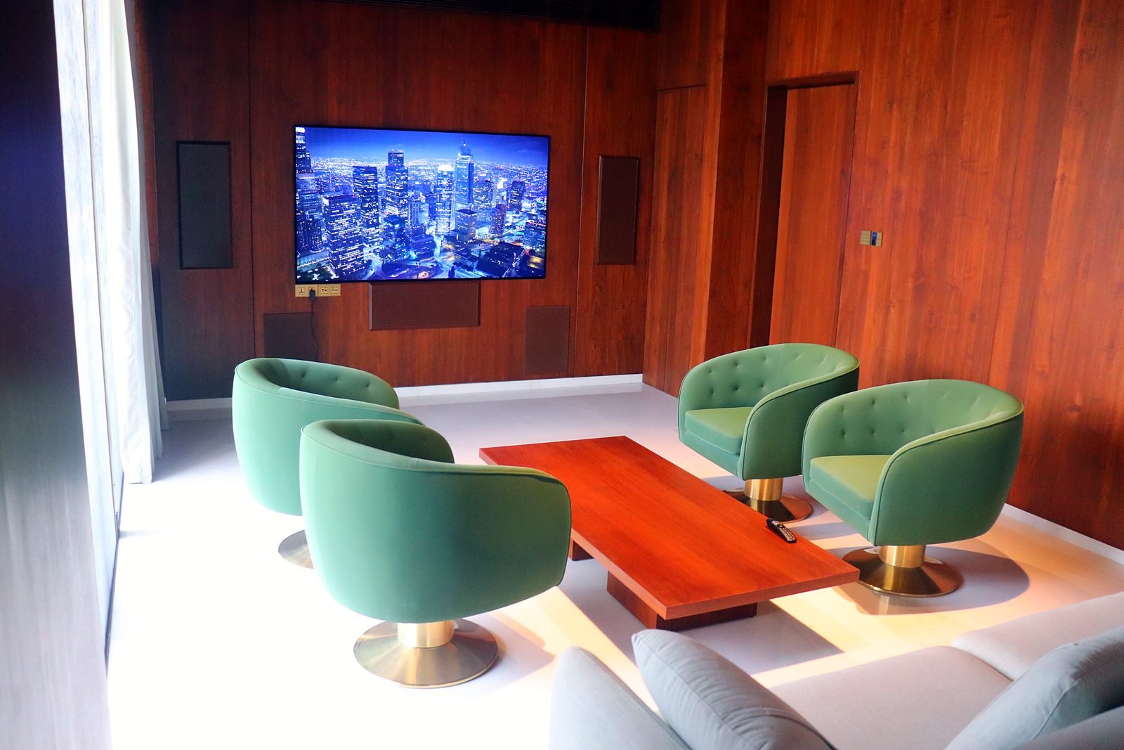 Lounge with green armchairs and wall-mounted TV in a Nagpur smart mansion