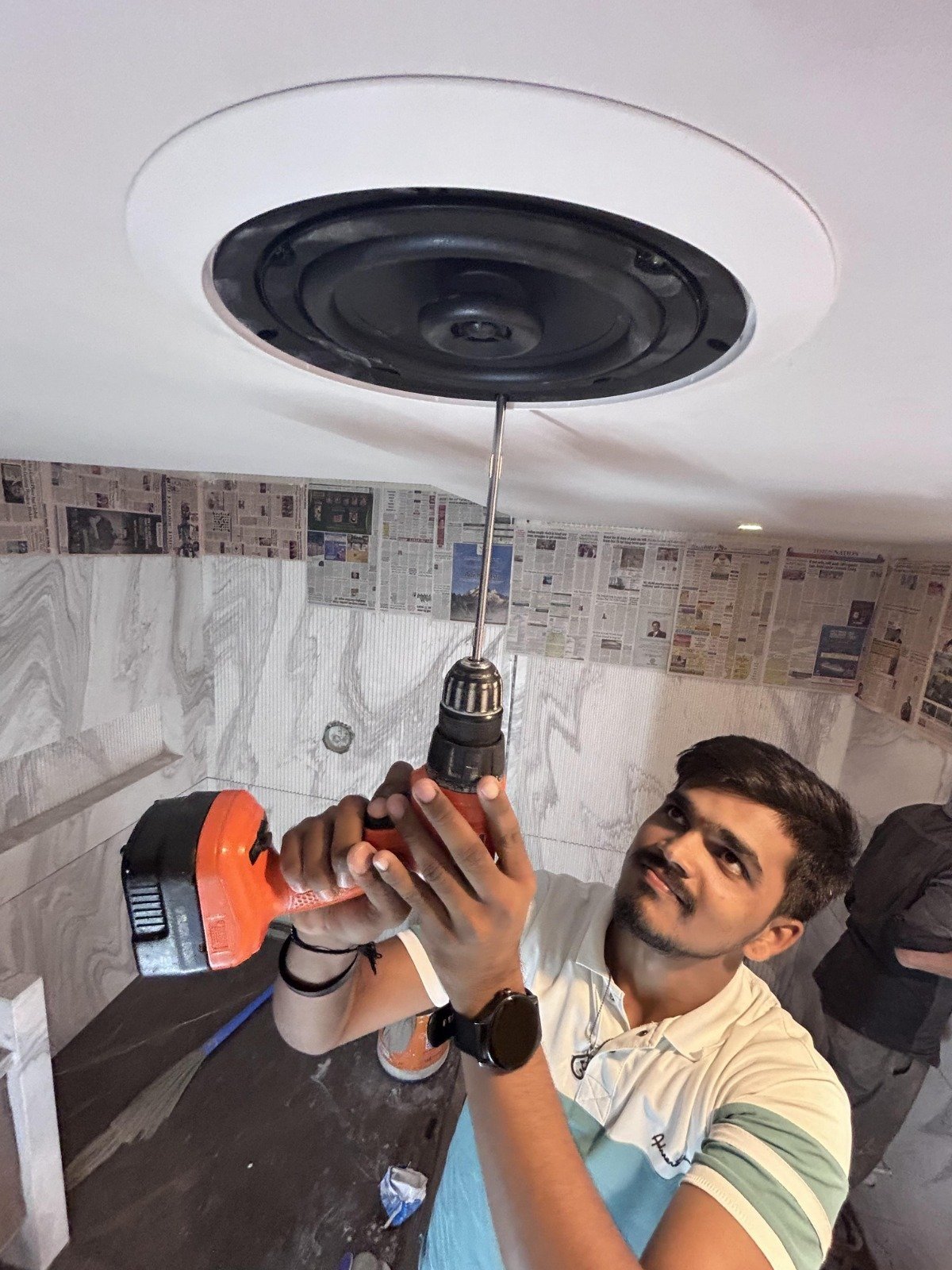Avenue Sound installer fixing a ceiling speaker to a ceiling during an outlet installation