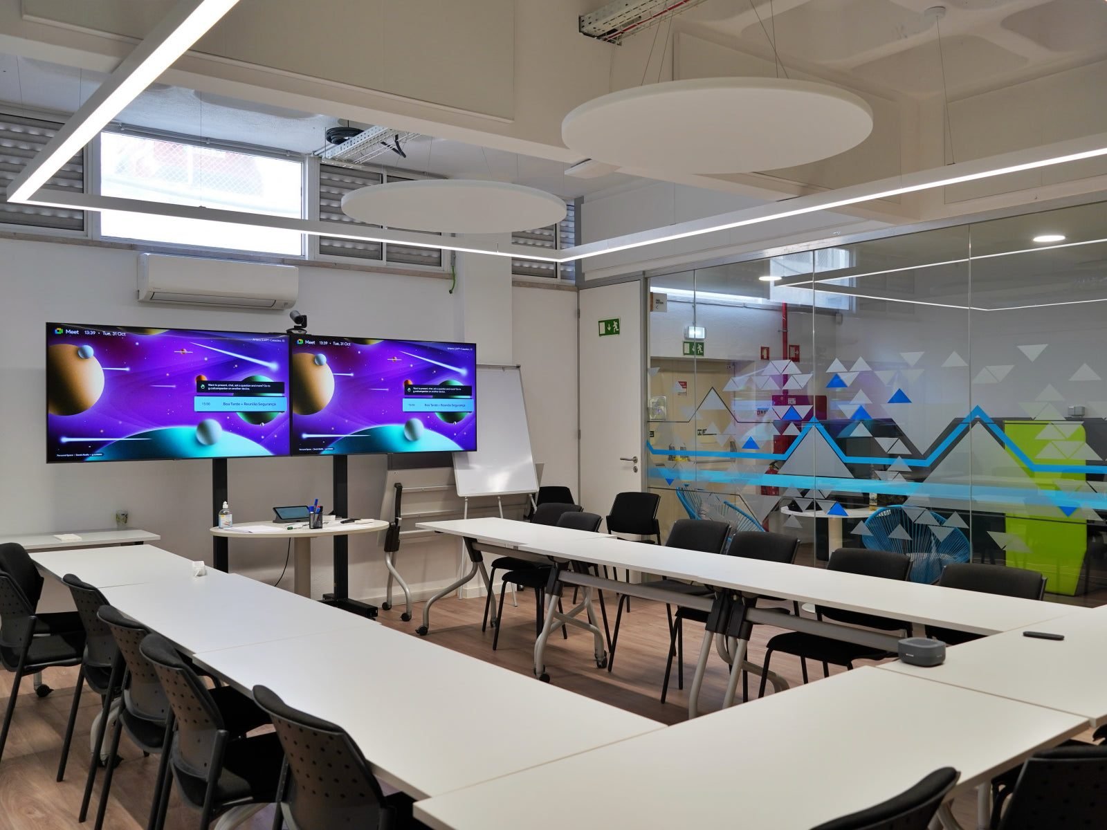 Vicoustic ceiling cloud absorbers hanging above a long meeting table in a conference room